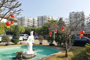 A courtyard with a fountain, a statue, and red lanterns. - Overseas Chinese Hotel (Foshan)