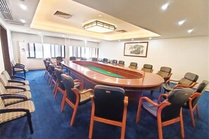 A conference room with a long table and chairs, a blue carpet, and a painting on the wall. - Overseas Chinese Hotel (Foshan)
