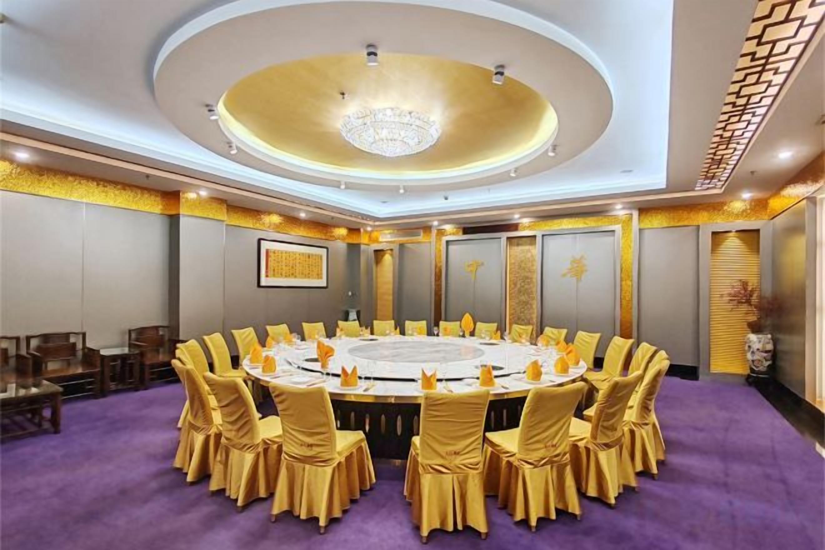 A conference room with a round table, chairs, and a chandelier.