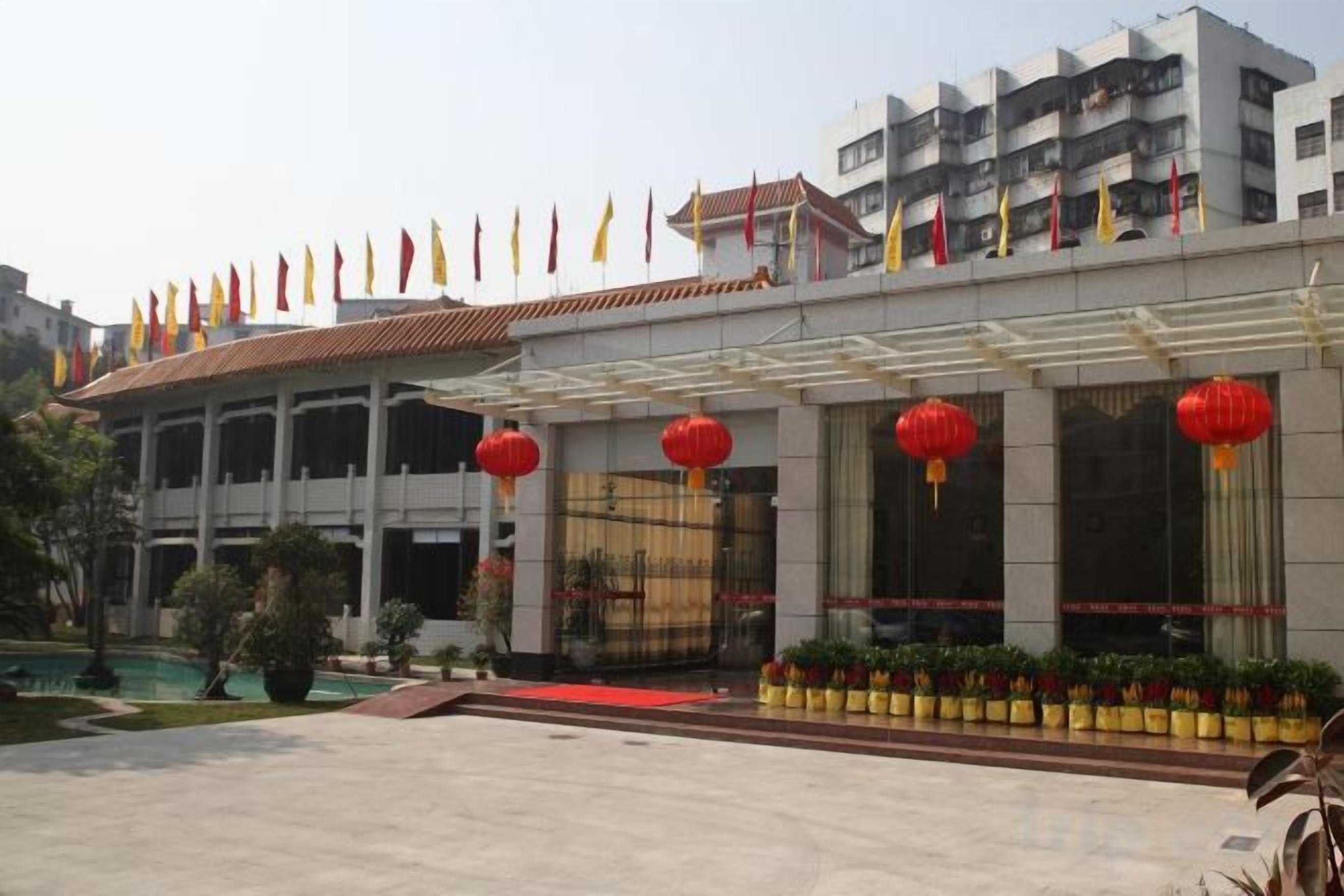 Un hotel con vestíbulo cubierto, varias banderas y faroles rojos.
