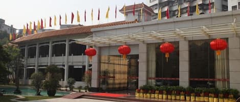 A hotel with a covered entrance, multiple flags, and red lanterns.