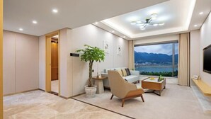 Een moderne woonkamer met een bank, salontafel en een groot raam met uitzicht op bergen.