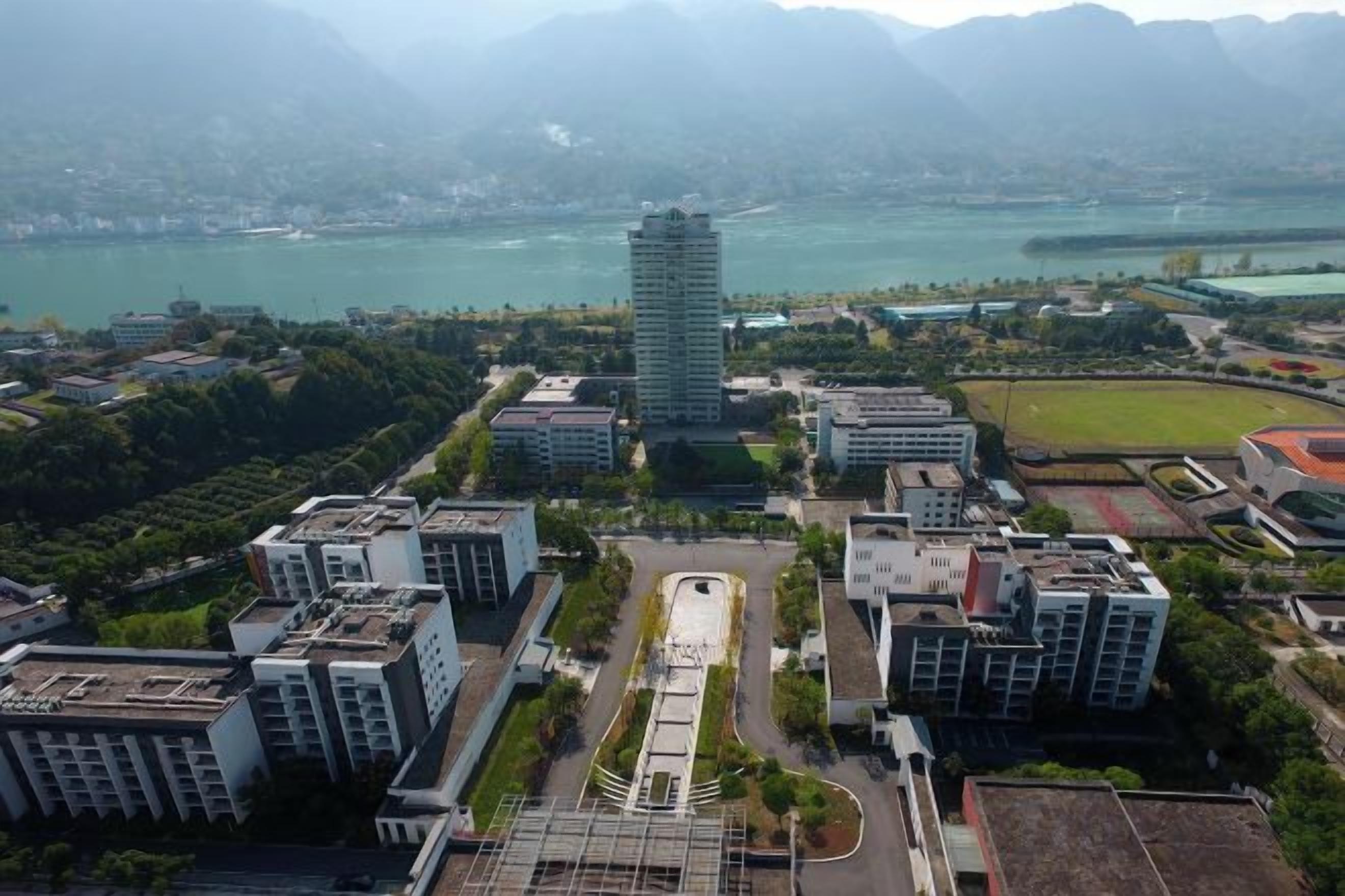 A high-rise building with a central courtyard surrounded by other buildings, overlooking a body of water and mountains.