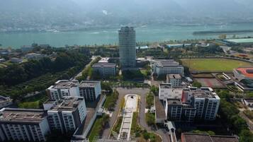 A high-rise building with a central courtyard surrounded by other buildings, overlooking a body of water and mountains.