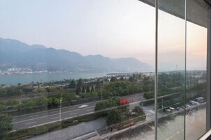 Vista desde una ventana que da a un paisaje urbano con un río, montañas y un puente.