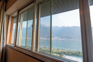 Una habitación con un ventanal grande con vistas a un lago y montañas.