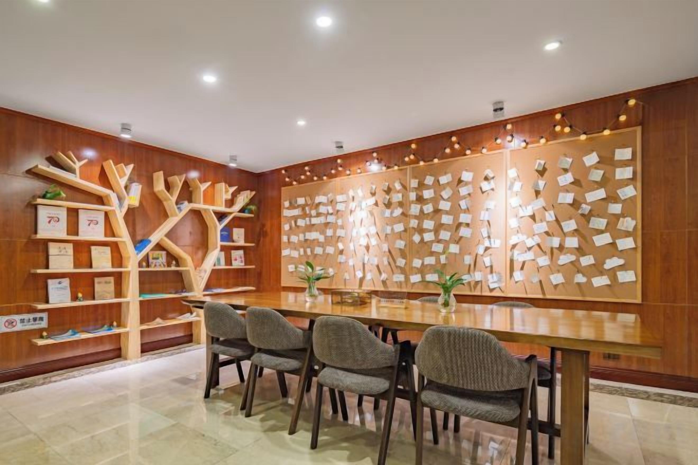 A conference room with a long table, chairs, and a wooden bookshelf.