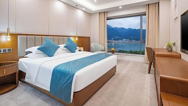 Een moderne hotelkamer met een groot bed, een bureau en uitzicht op zee.