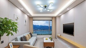 Een moderne woonkamer met een bank, salontafel, televisie en een groot raam met uitzicht op de bergen.