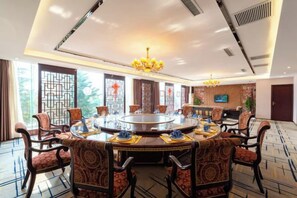 A conference room with a round table, chairs, and a television screen.