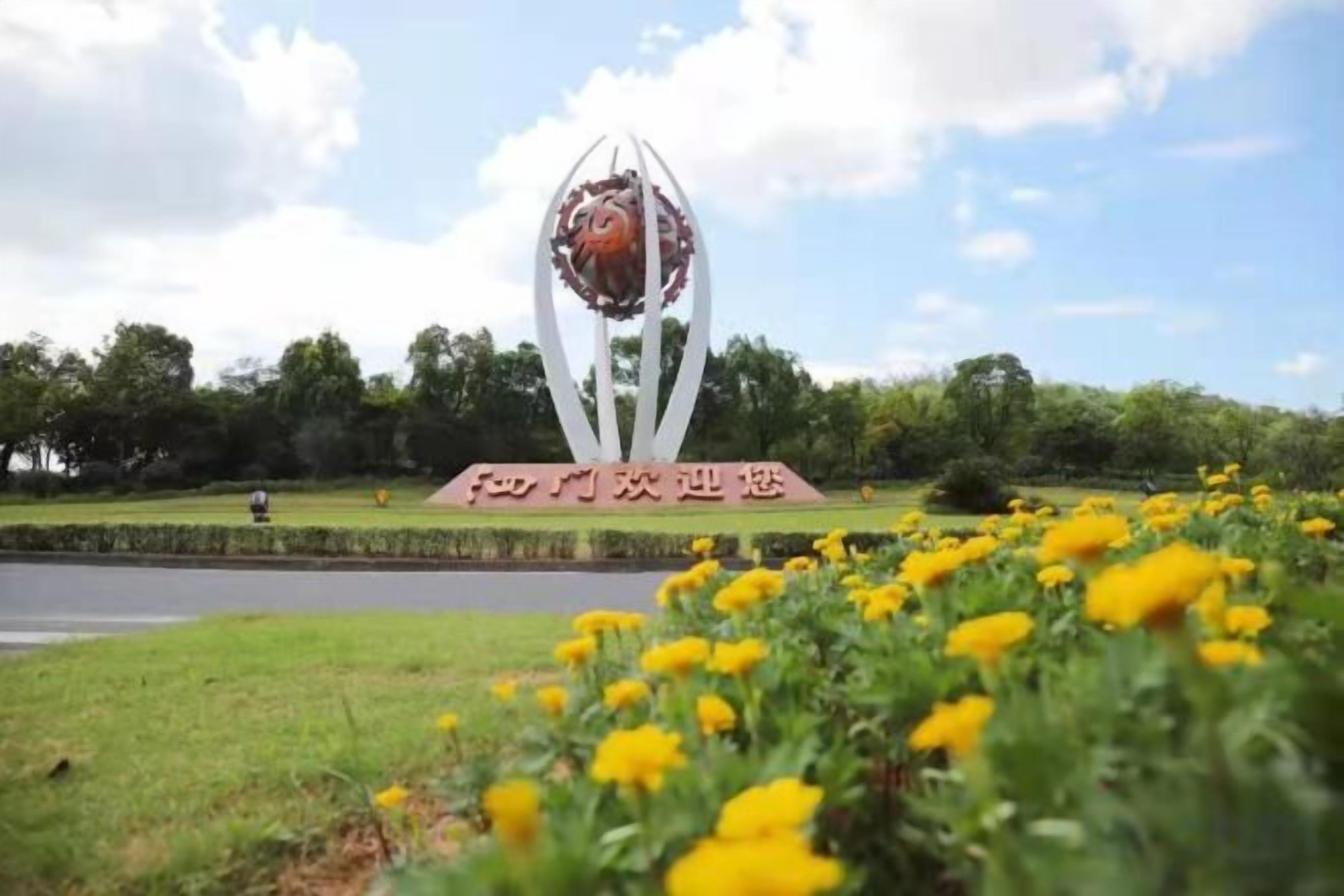Un parque con una escultura central y un cartel.