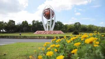 Un parque con una escultura central y un cartel.