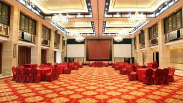 A large conference room with round tables and chairs, a carpeted floor, and chandeliers.