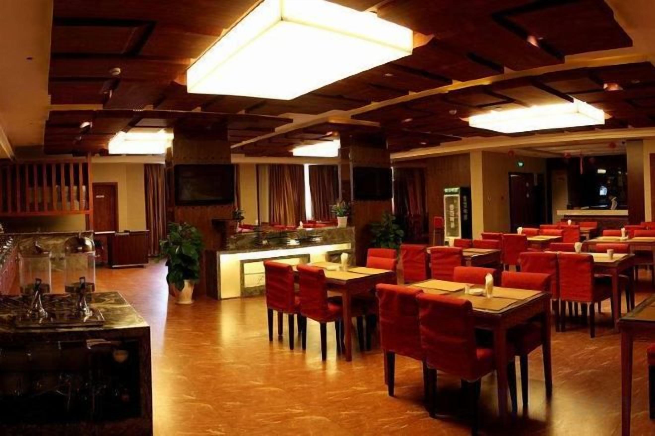 Un restaurante con vigas de madera en el techo, una zona de bar y sillas rojas.