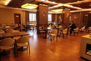 A spacious dining area with multiple tables and chairs, large pillars, and a high ceiling with exposed beams. - Qindao International Hotel (Ningbo)