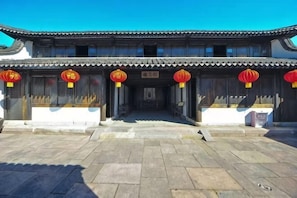 A traditional building with a tiled roof, wooden doors, and red lanterns. - Qindao International Hotel (Ningbo)