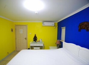 A hotel room with a bed, a desk with a lamp, a wall-mounted air conditioner, and a door. - Gulangyu Fuxing No.10 Family Inn - Xiamen (Xiamen)