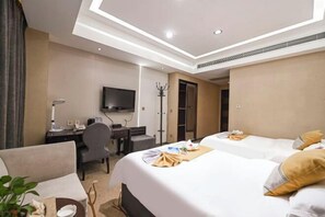 A hotel room with two beds, a desk, a chair, a television, and a coat rack. - Beibingyang Hotel (Yangquan)