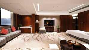 Ein modernes Hotelzimmer mit einer Couch, einem Bett, einem Schreibtisch und einem Fernseher.
