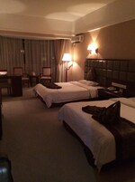 Habitación de hotel con dos camas, un escritorio, sillas y una lámpara.