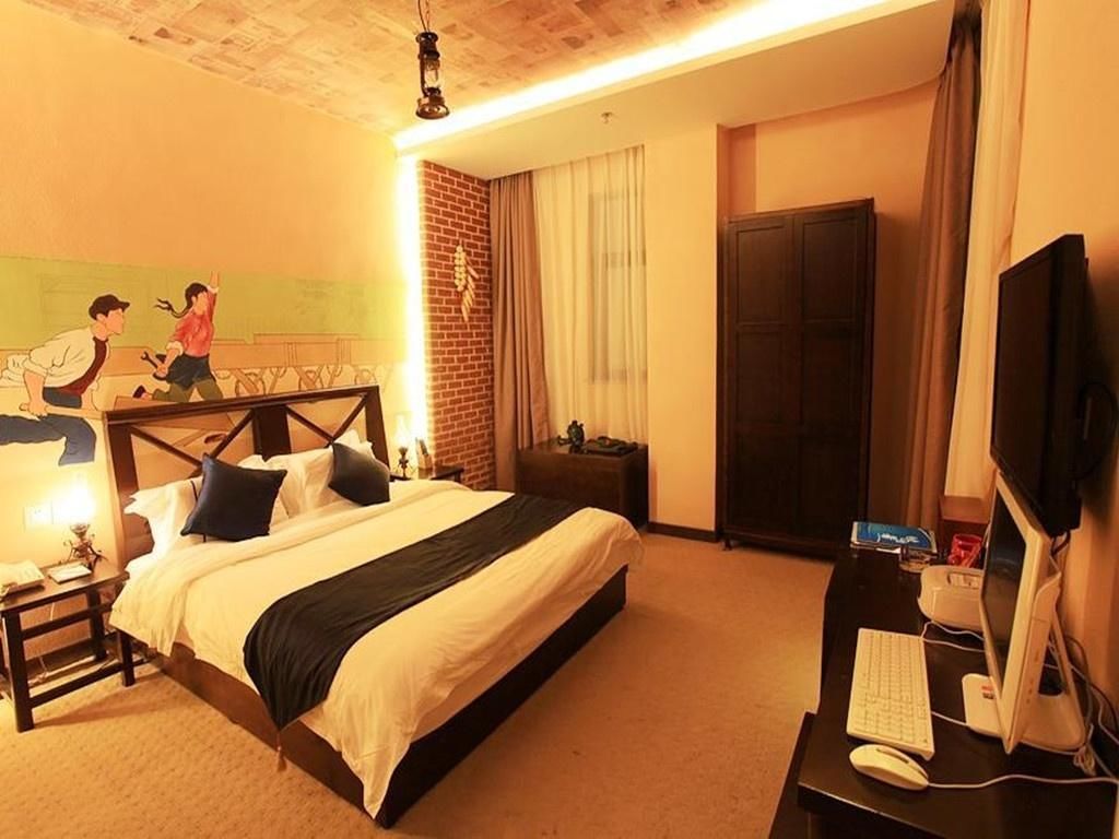 A hotel room with a bed, desk, computer, and a television.