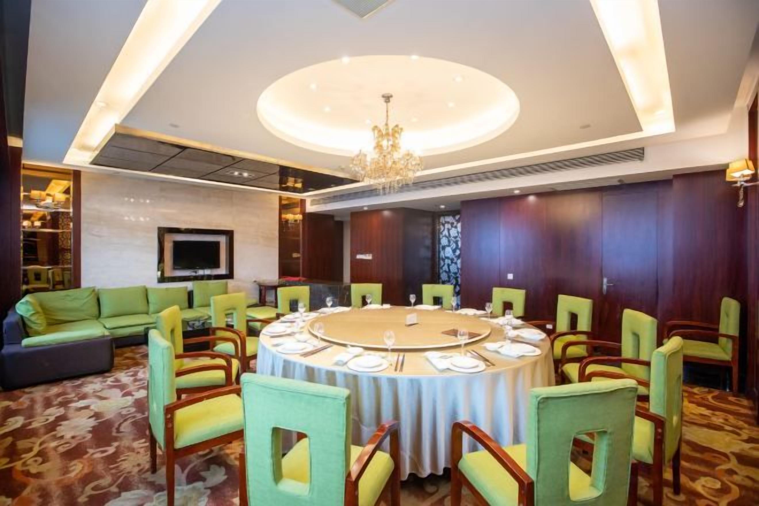 Un salón de conferencias con una mesa redonda, sillas y una televisión.