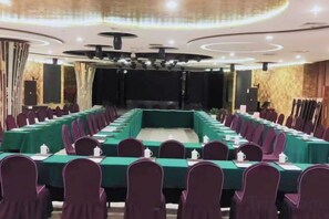 A conference room with a long table, chairs, and a stage. - Haina Baichuan Hotel (Ningbo)