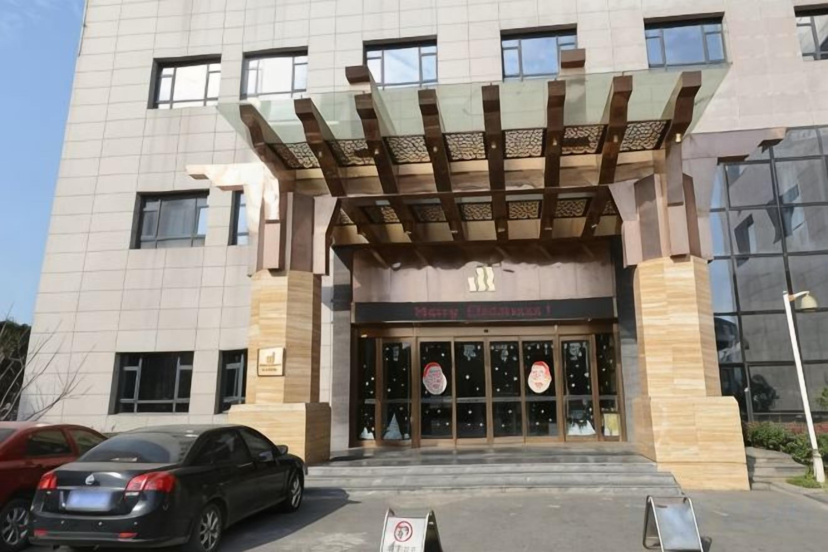 A building with a modern entrance featuring a wooden canopy and a glass door with a circular logo.