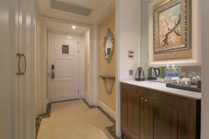 A hallway with a white door, a wooden cabinet with a mirror, and a framed picture on the wall. - Haina Baichuan Hotel (Ningbo)