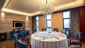 A conference room with a round table, blue chairs, and a chandelier.