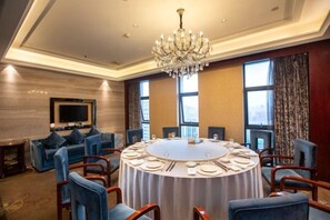 Un salón de conferencias con una mesa redonda, sillas azules y una araña de cristal.