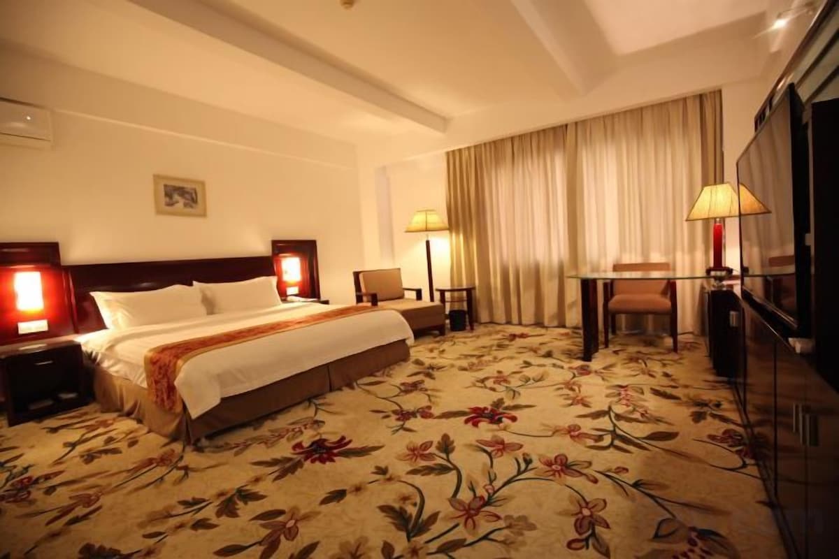Une chambre d’hôtel équipée d’un lit, de lampes de chevet, d’un bureau et d’une télévision.