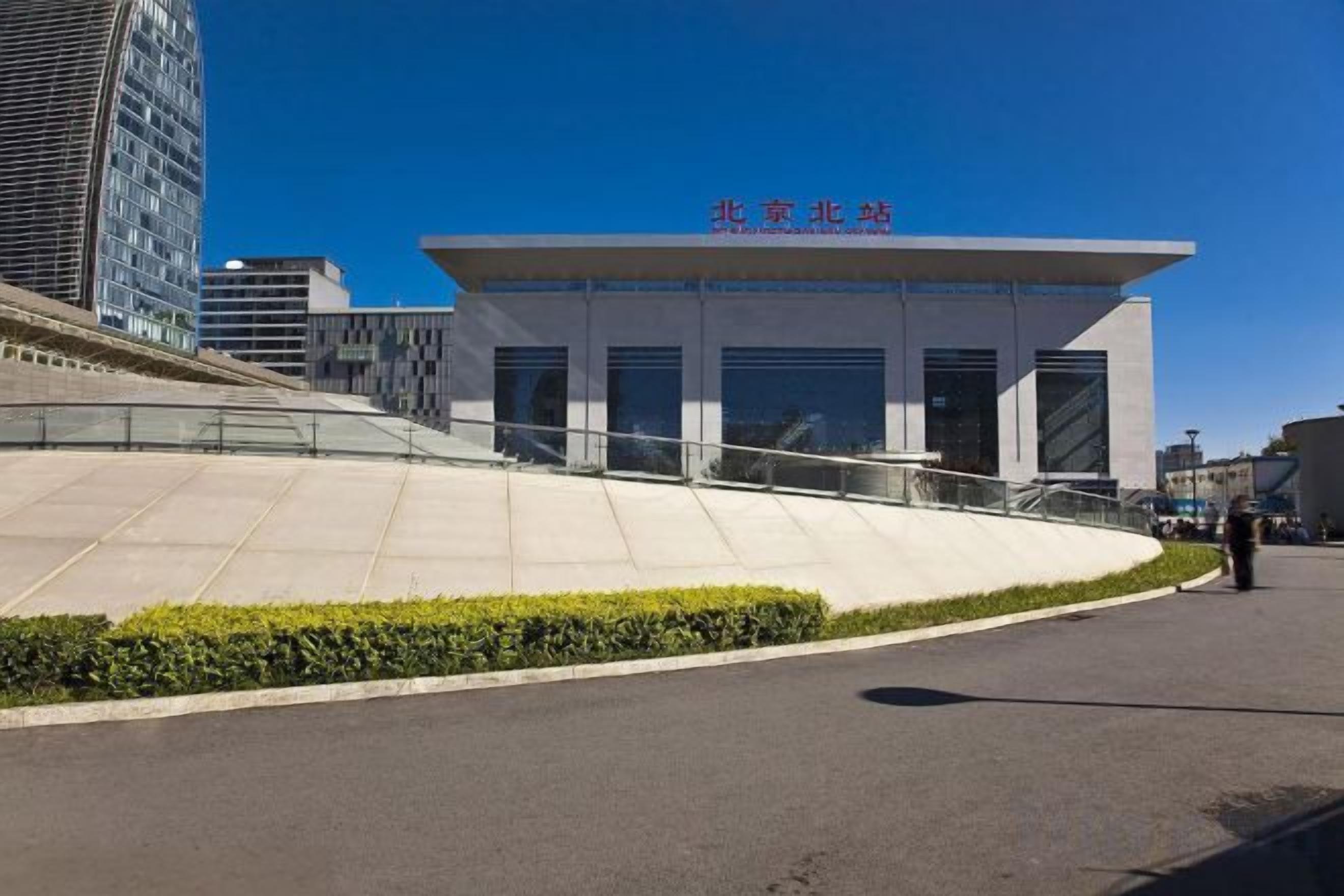 Un edificio moderno con techo plano y amplios ventanales, rodeado de zonas ajardinadas con un sendero curvo.