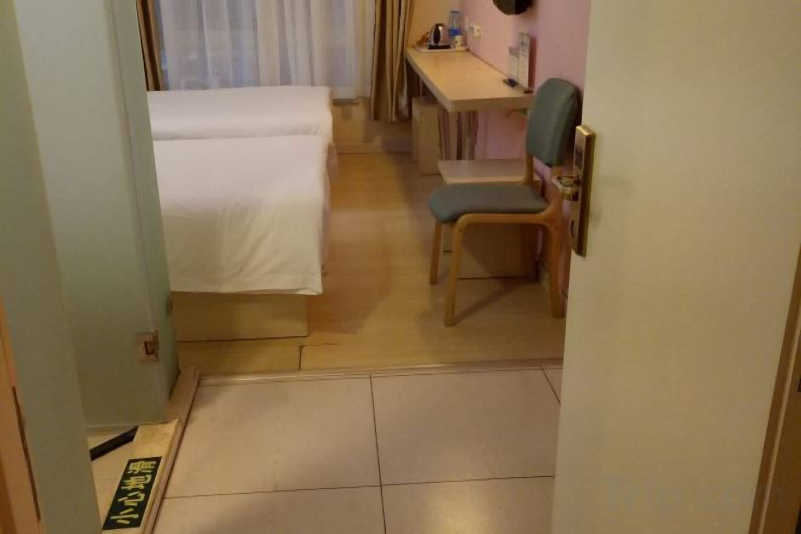 A hotel room with a bed, a desk, a chair, and a small table.