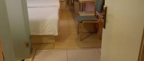 A hotel room with a bed, a desk, a chair, and a small table.