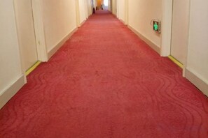 A red carpeted hallway with a fire alarm on the wall. - Hejia Inn (Beijing Fuwai Hospital) (Beijing)