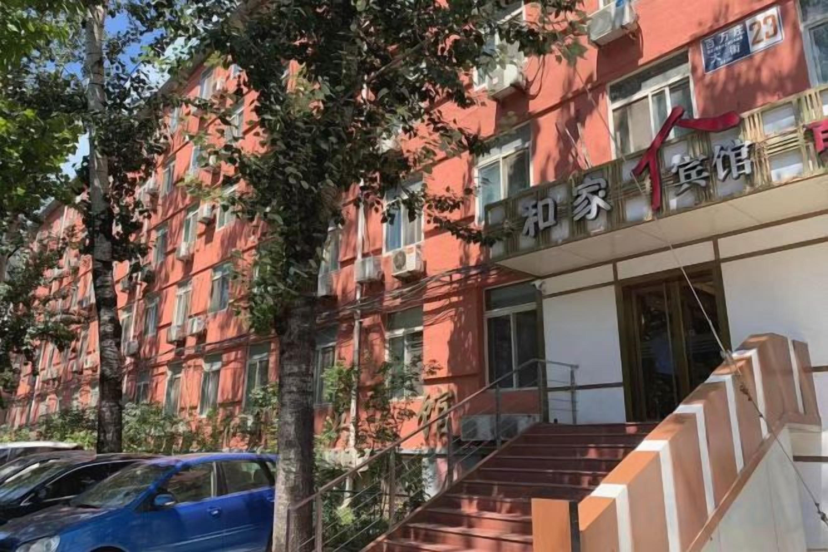 A red building with multiple windows and a staircase leading to the entrance.