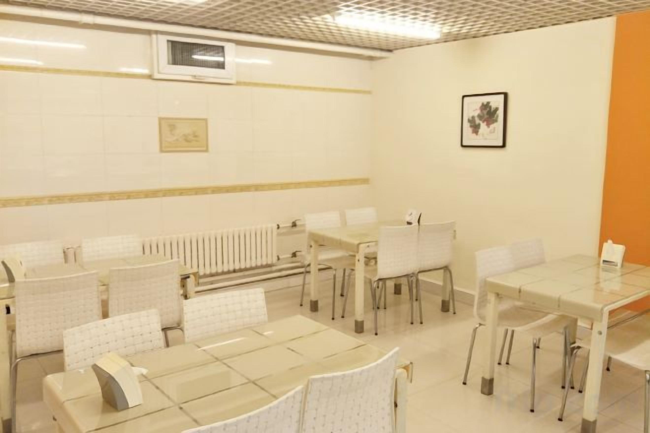 A conference room with multiple tables and chairs, a radiator, and a framed picture on the wall.
