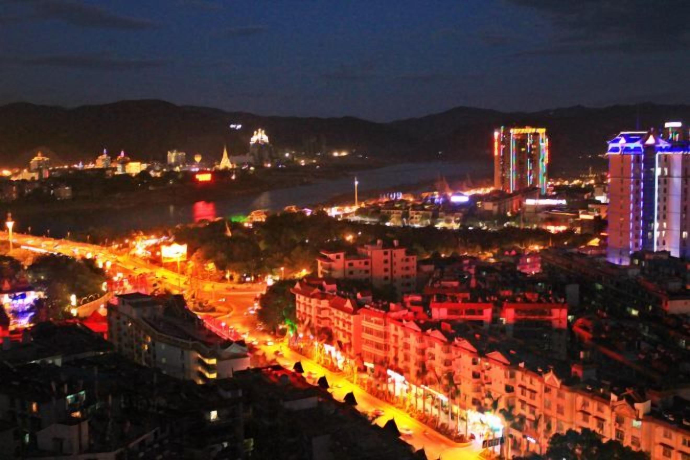 A nighttime cityscape with illuminated buildings and a river.