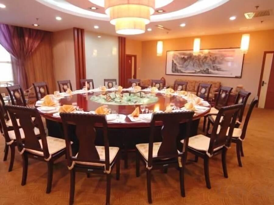 Uma mesa de jantar redonda com cadeiras, um candelabro e um quadro na parede.