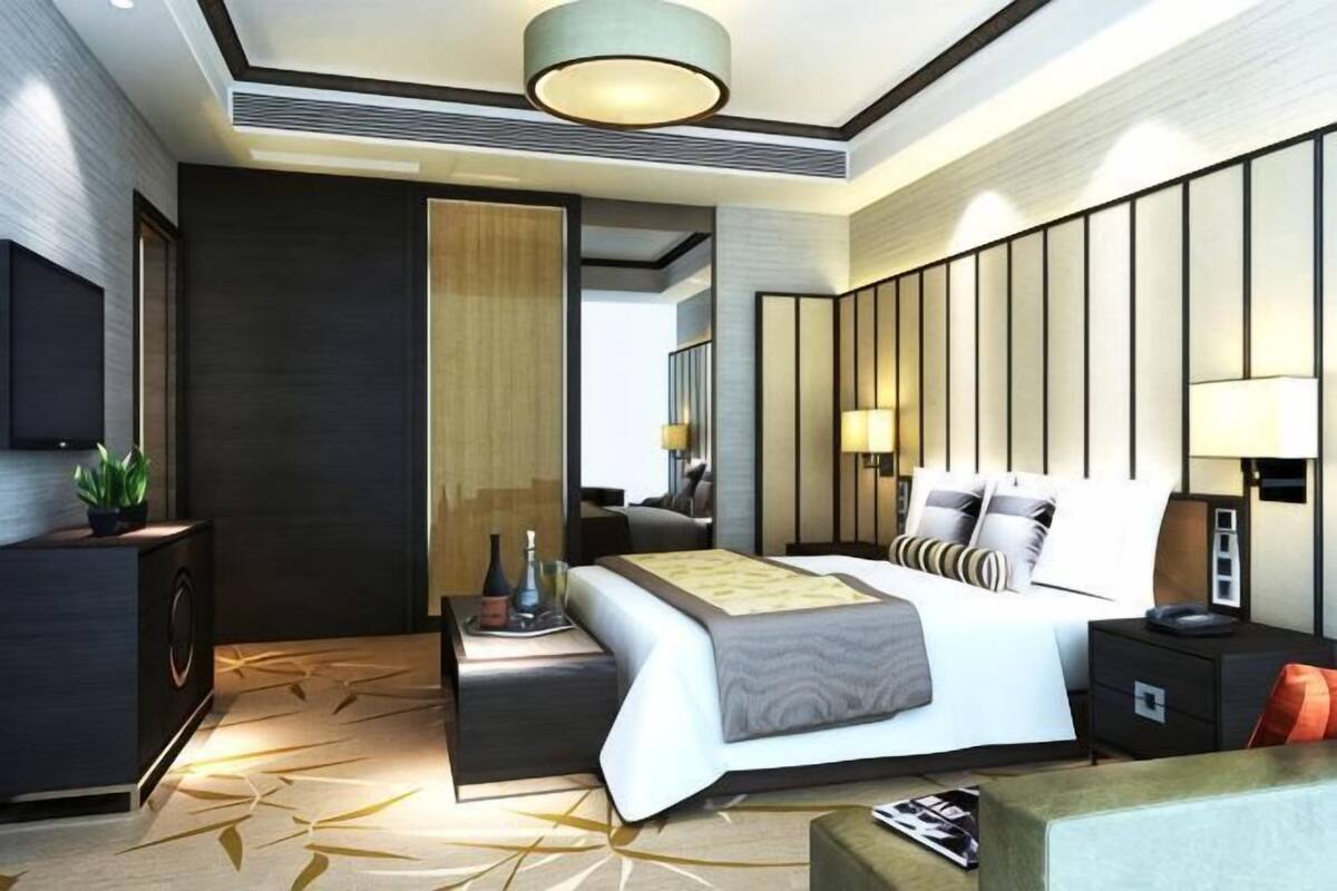A modern hotel room with a bed, bedside tables, a TV, a desk, and a large mirror.