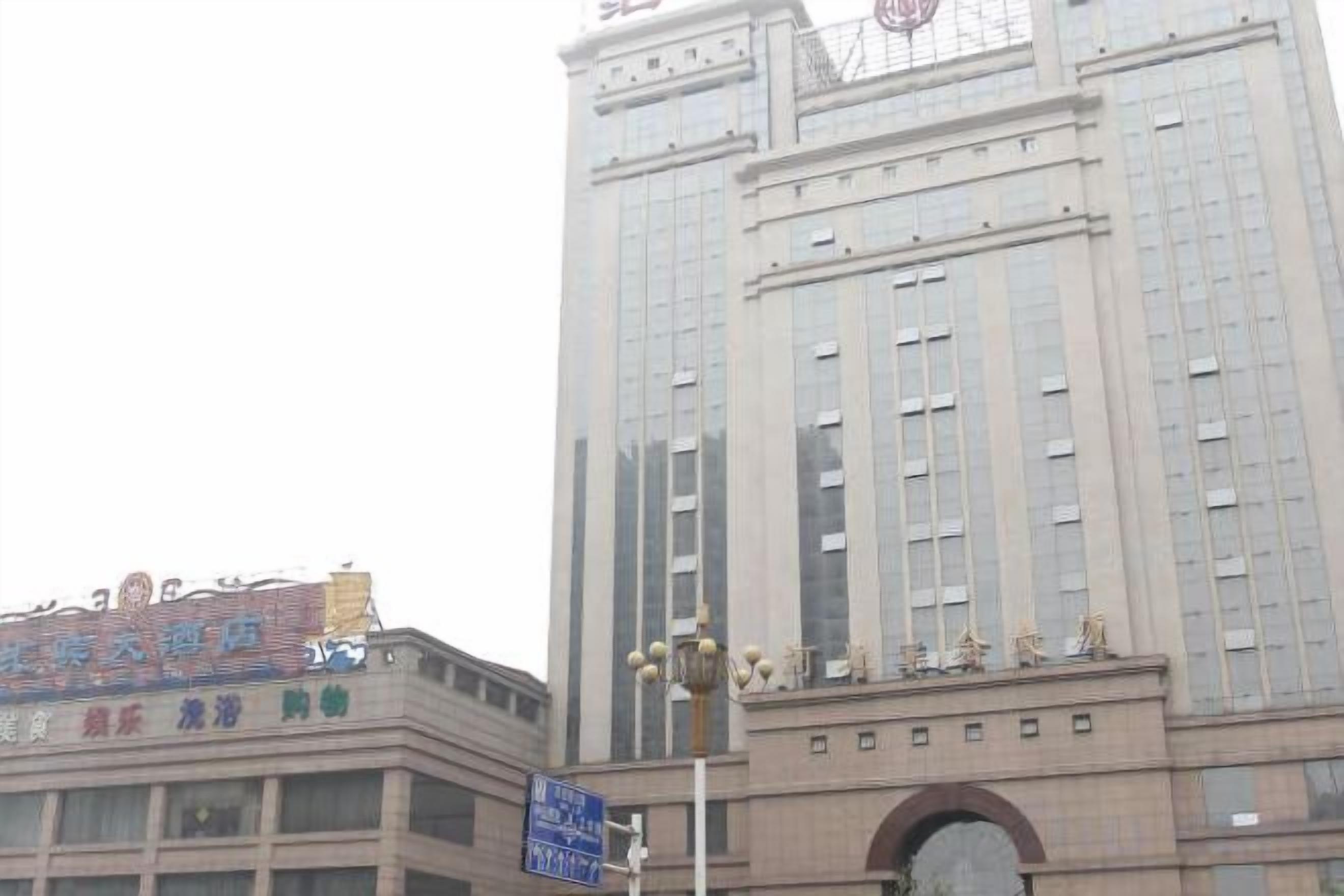 Un edificio alto con una torre dell'orologio in cima, un cartello con caratteri cinesi e un lampione in primo piano.