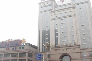 Un grand immeuble surmonté d’une horloge, une enseigne avec des caractères chinois et un lampadaire au premier plan.