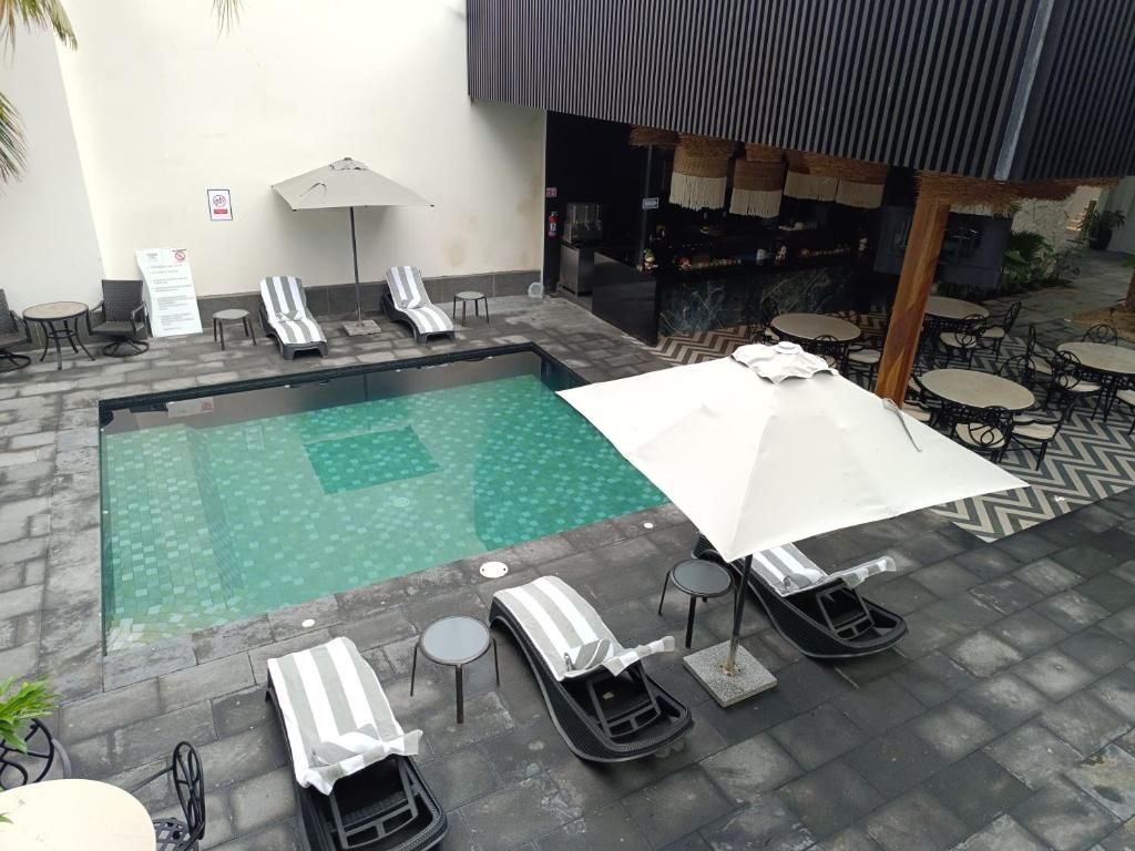 Un área de piscina con sillones de descanso, sombrillas y un bar.