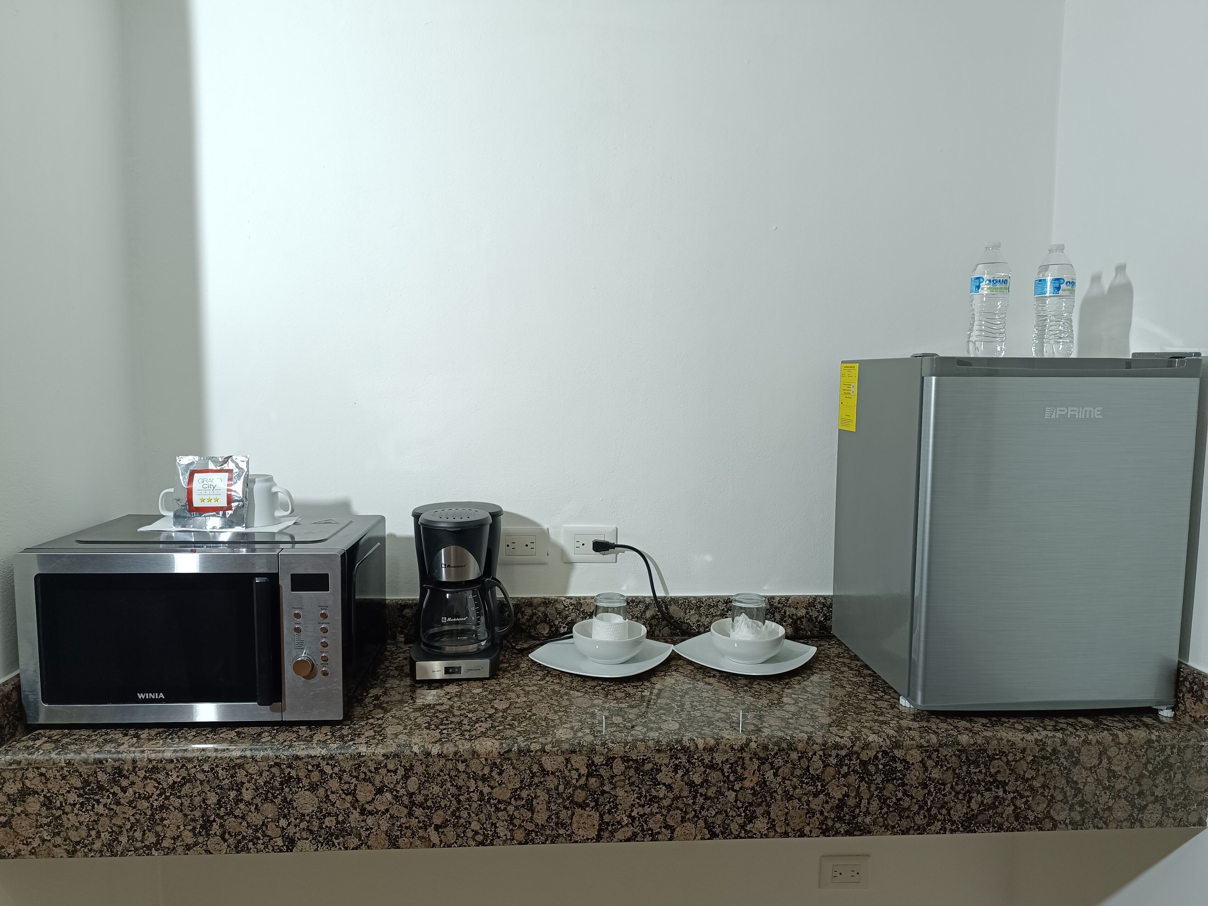 A kitchenette with a microwave, coffee maker, and refrigerator.