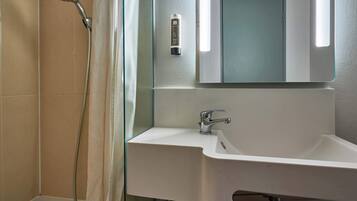 Un bagno con doccia, lavandino, specchio e porta asciugamani.