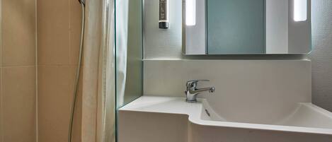 Une salle de bain équipée d’une douche, d’un lavabo, d’un miroir et d’un porte-serviettes.