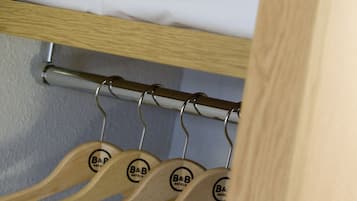 Una habitación de hotel con una cama bien hecha, una toalla y perchas de madera con el logotipo del hotel.