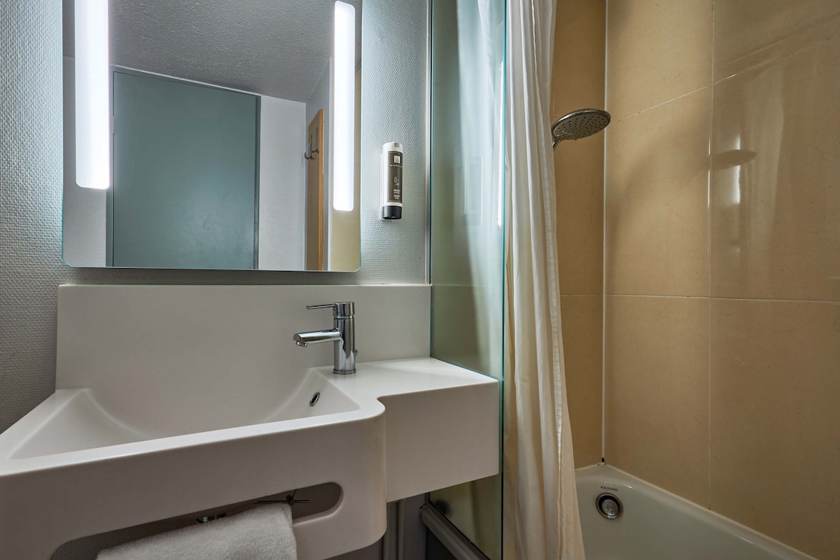 Une salle de bain avec un lavabo blanc, un miroir et une douche.