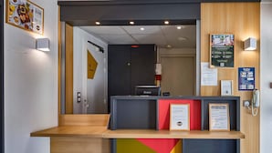 Een receptiebalie met een houten aanrecht, een informatiebord in zwart en rood, en een ingelijst certificaat.
